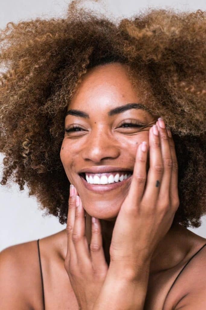 Woman of Color Smiling with Hands on Face