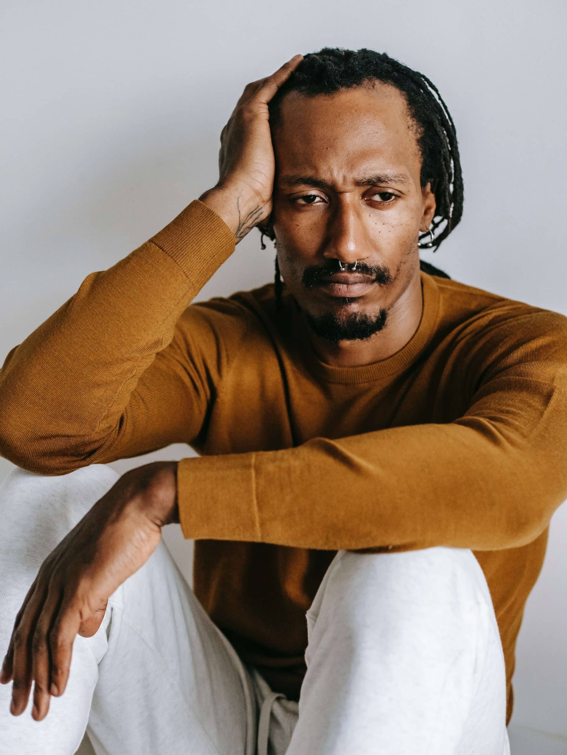 man sitting down on the floor with his hand on his head in despair 